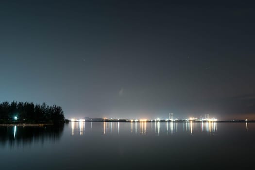 Coastline view of sea, pier, sky during dusk with lights reflection on water somewhere in Asia