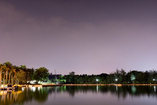 Horizontal view of lake and nature during dusk with night stars and smooth reflection on waters somewhere in Asia