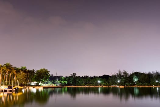 Horizontal view of lake and nature during dusk with night stars and smooth reflection on waters somewhere in Asia