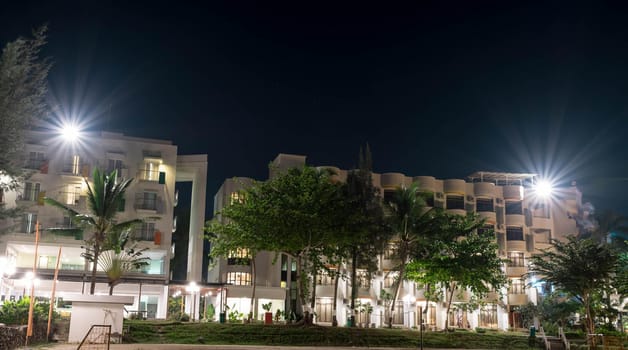 Hotel in a beach resort during night with bright lights and trees with clear sky and stars somewhere in Asia