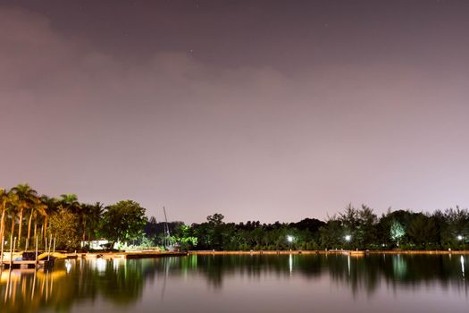 Horizontal view of lake and nature during dusk with night stars and smooth reflection on waters somewhere in Asia