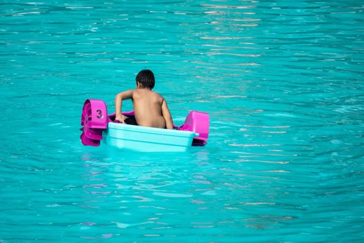 Child playing a water pedal boat in a swimming pools