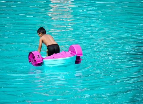 Child playing a water pedal boat in a swimming pools