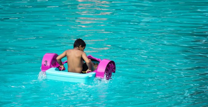 Child playing a water pedal boat in a swimming pools