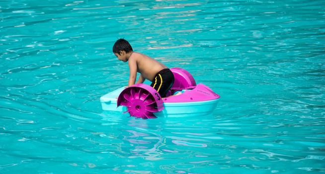 Child playing a water pedal boat in a swimming pools