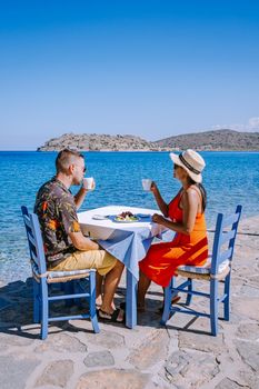 Crete Greece Plaka Lassithi with is traditional blue table and chairs and the beach in Crete Greece. Paralia Plakas, Plaka village Crete, couple on vacation holiday in Greece