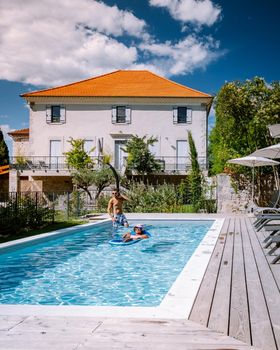 French vacation home with wooden deck and swimming pool in the Ardeche France Europe. Couple relaxing by the pool with wooden deck during luxury vacation at an holiday home in South of France