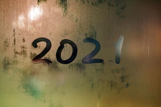 digit 2021 handwritten on wet night window glass surface, close-up with selective focus