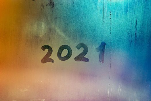 digit 2021 handwritten on wet night window glass surface, close-up with selective focus