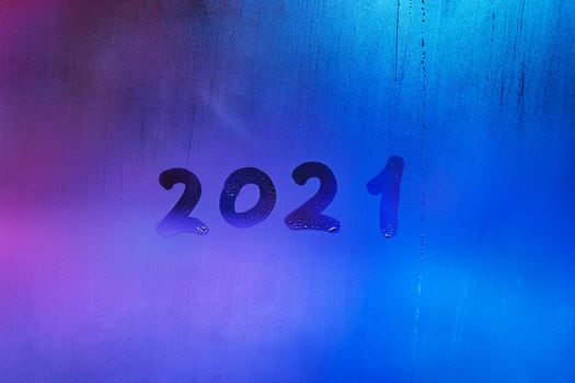 digit 2021 handwritten on wet night window glass surface, close-up with selective focus