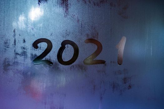 digit 2021 handwritten on wet night window glass surface, close-up with selective focus