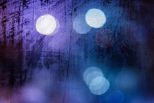 an abstract background of night wet window glass with smudges in blue tone gamma.