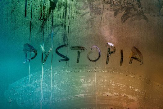the word dystopia handwritten on wet window glass surface close-up with selective focus and color gradient