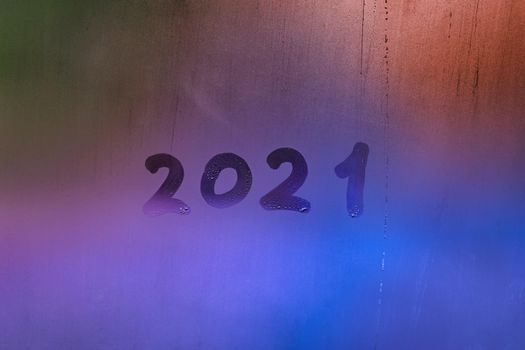 digit 2021 handwritten on wet night window glass surface, close-up with selective focus