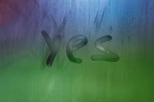 word yes handwritten on foggy window glass surface, close-up with selective focus
