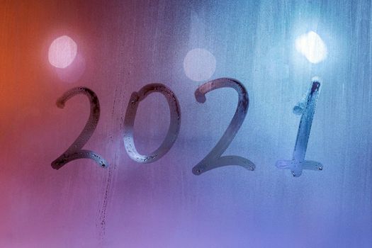 digit 2021 handwritten on wet night window glass surface, close-up with selective focus