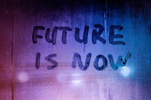 words future is now handwritten on night foggy window glass surface, close-up with selective focus