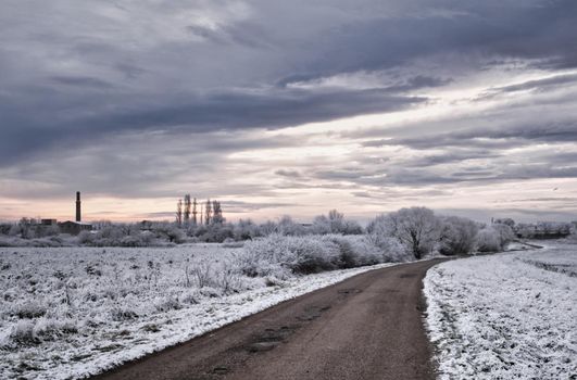 Lonely road at cloudy sunrise in winter