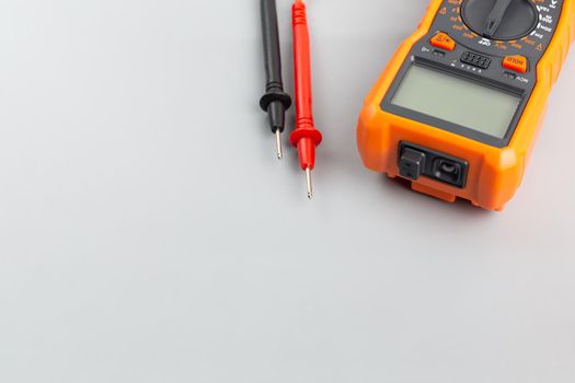 close-up view of digital electrical multimeter with probe tips on gray background