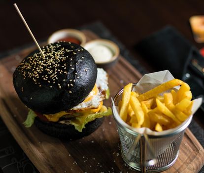 Black bread burger with French fries potatoes, ketchup