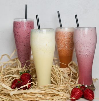 Fruit milky cocktails with strawberry on a straw