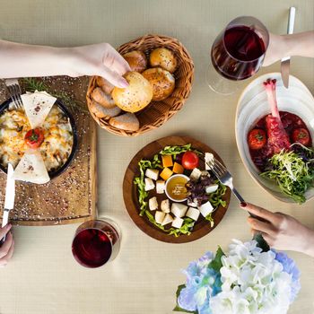 2 woman eating red beef meat meal, fried egg with red wine, top view