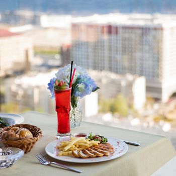 Fried chicken with french fries, red cocktail and city view