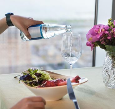 Tasty red beef meat meal with flower, Pouring water to a glass from bottle