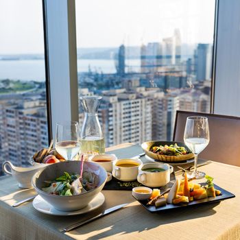 Chicken salad, cheese with different soups on the table, city view