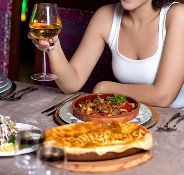 Woman drinking white wine with meat meal at the restaurant close up