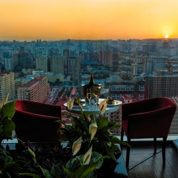 Champagne bottle and glasses, cake at restaurant with sunset city view