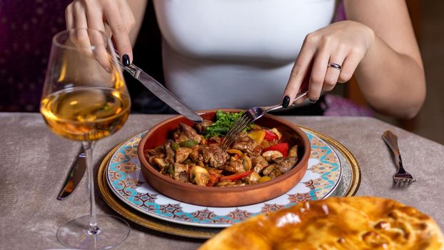 Woman eating meat meal with white wine at the restaurant