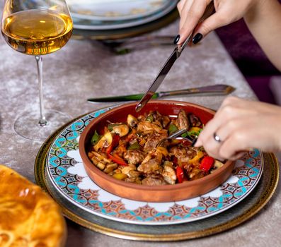 Woman eating meat meal with white wine at the restaurant