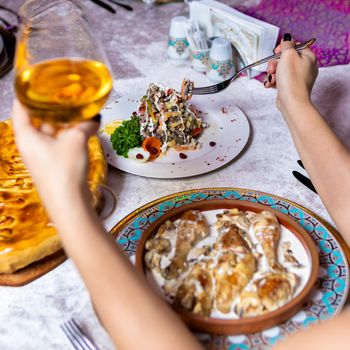 Woman drinking white wine with meat meal, top view