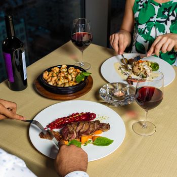 Couple at dinner eating steak, seafood with wine