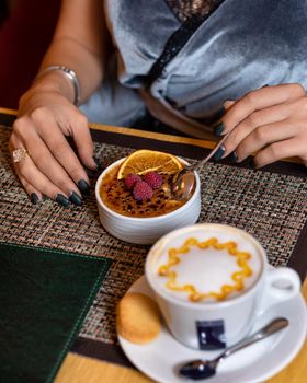 Woman eating raspberry dessert with latte coffee