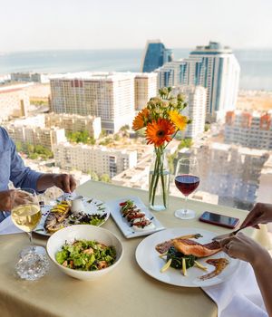 Couple eating fish meal with lemon and white wine