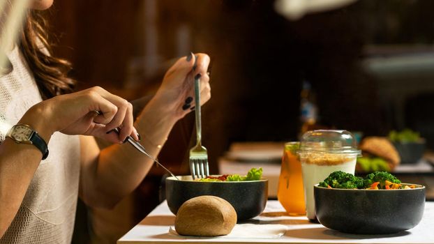 Woman eating tasty chicken salad with dessert