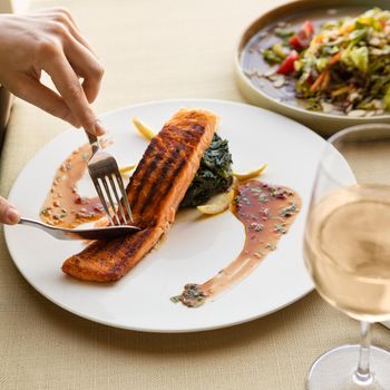 Cutting beautiful salmon meal with lemon and white wine