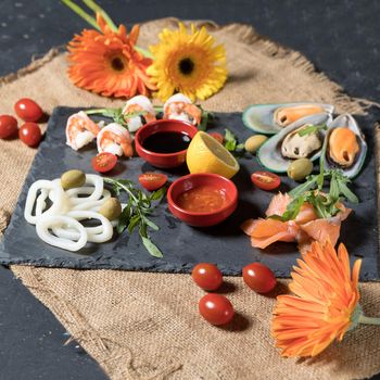 Fresh fish and seafood arrangement on black stone background