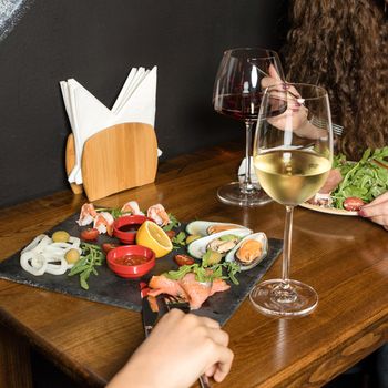 Two woman eating meat salad, snack with wine