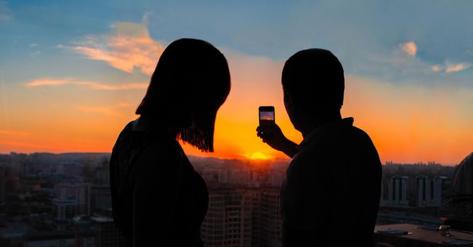 Couple taking photo of beautiful sunset city view
