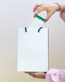 Woman putting box to the white shopping bag