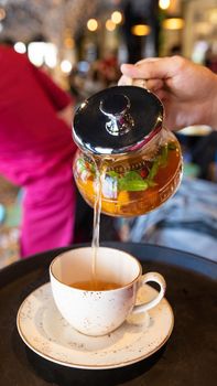Pouring yellow natural tea to the cup