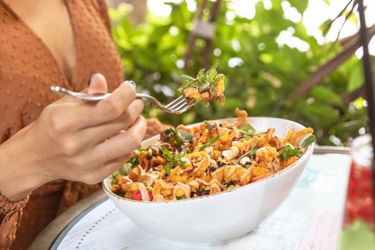 Woman eating chicken salad with green background