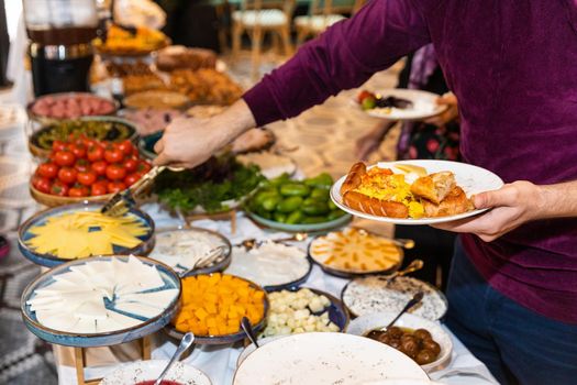 Man taking food from breakfast table at the restaurant