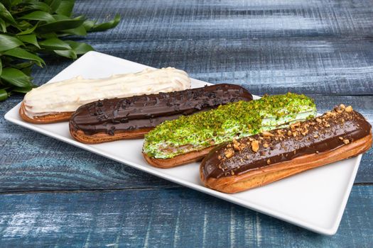 Tasty chocolate eclair cakes with leaves on the blue background