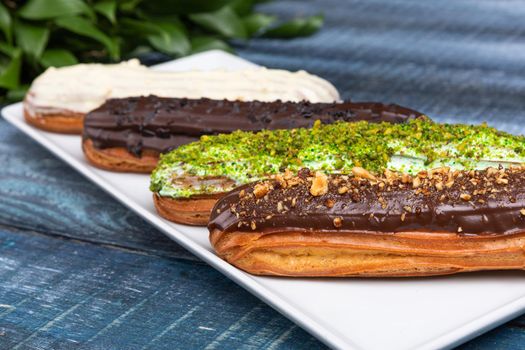 Tasty chocolate eclair cakes with leaves on the blue background