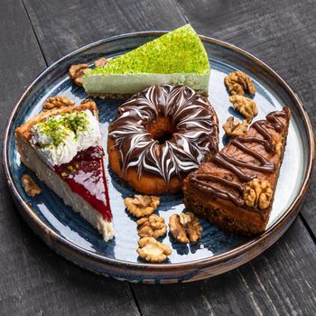 Beautiful doughnut, chocolate cake, tiramisu on the blue plate, top view