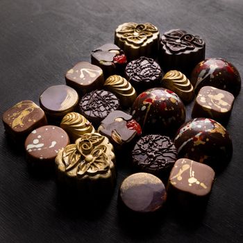 Luxury chocolate pieces on the black background, top view